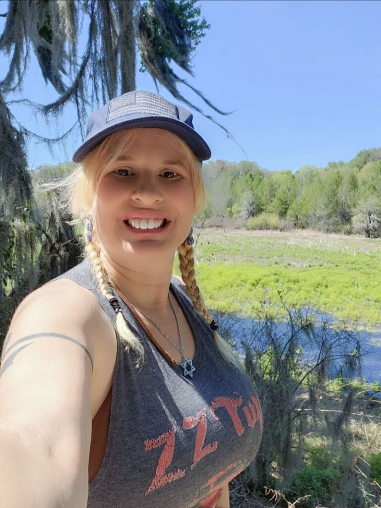 Daisy Chain is smiling in front of the vibrant green wetlands with Spanish moss at Alligator Lake Park.